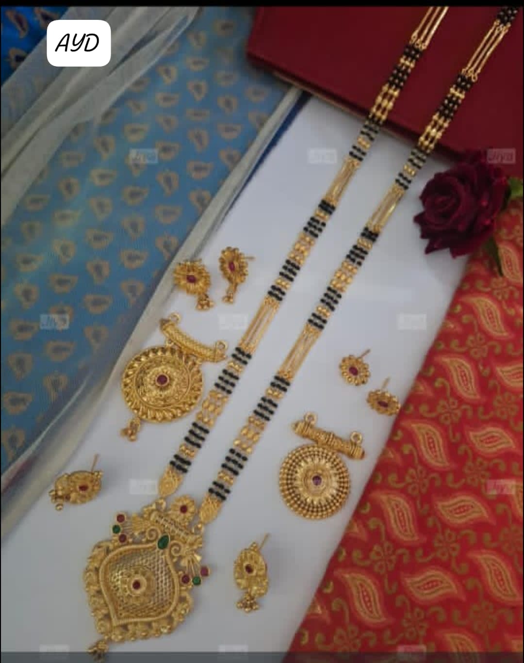 Gold jewelry set on a decorative box with a red flower